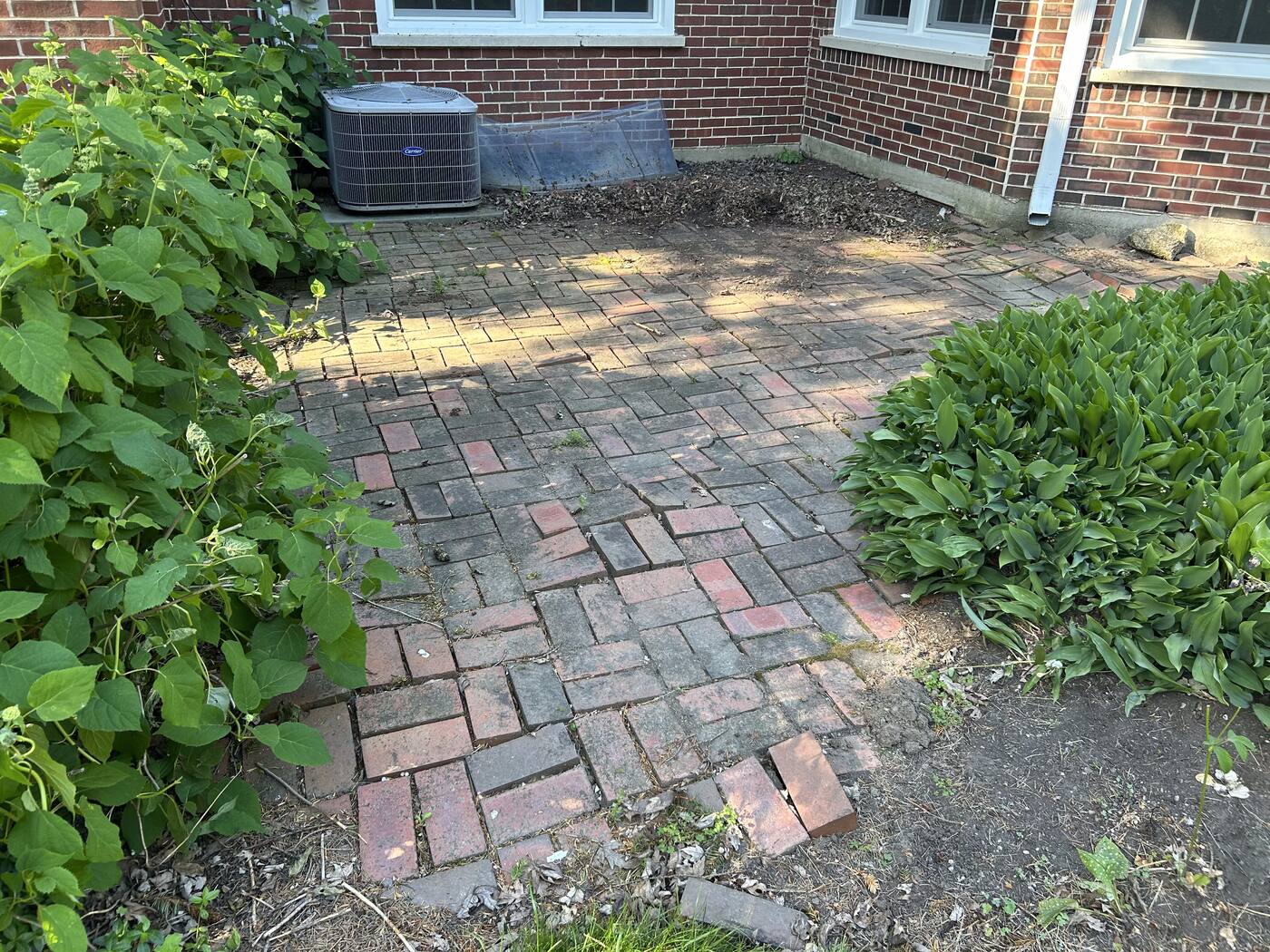 Old, worn brick patio with uneven, weathered pavers before renovation