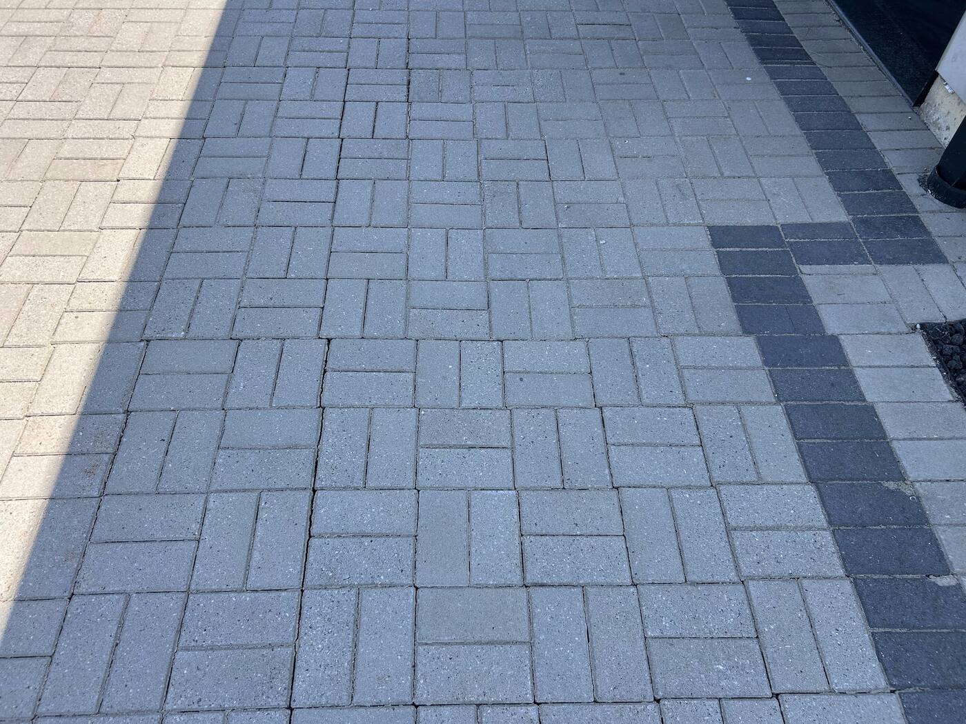 Finished gray herringbone paver patio with dark accent border stripe