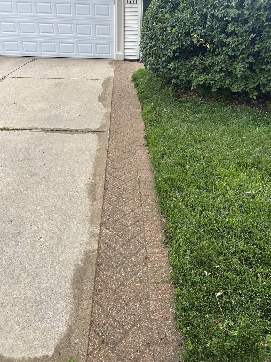 Brick paver edging strip running along a concrete driveway beside a garage