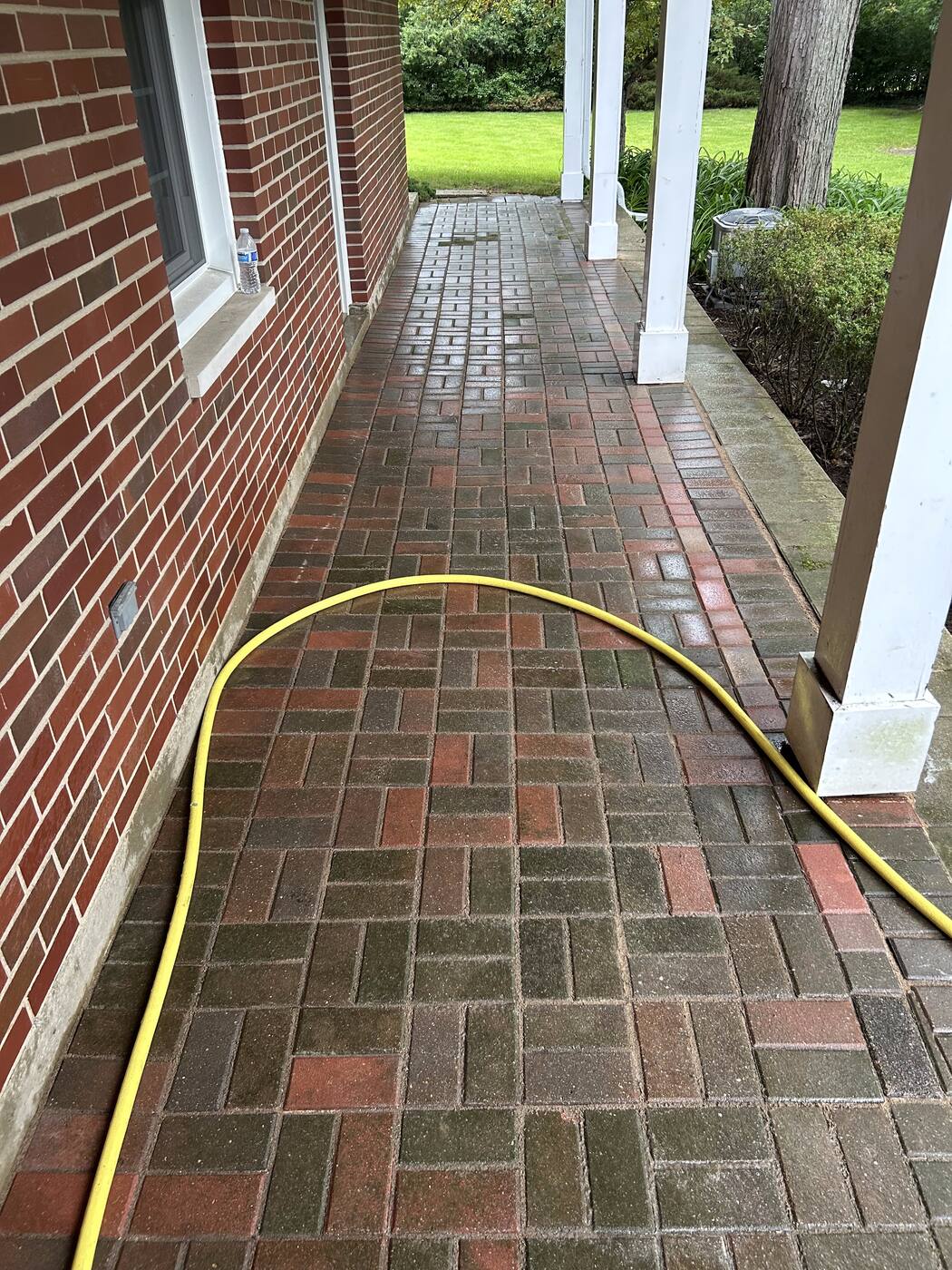 Brick paver walkway running alongside a covered front porch with white columns