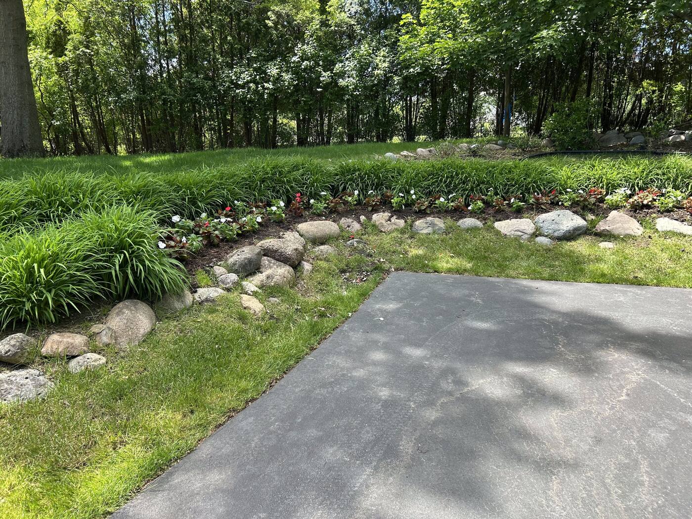 Stone-edged planting border with ornamental grasses and mixed flowering perennials